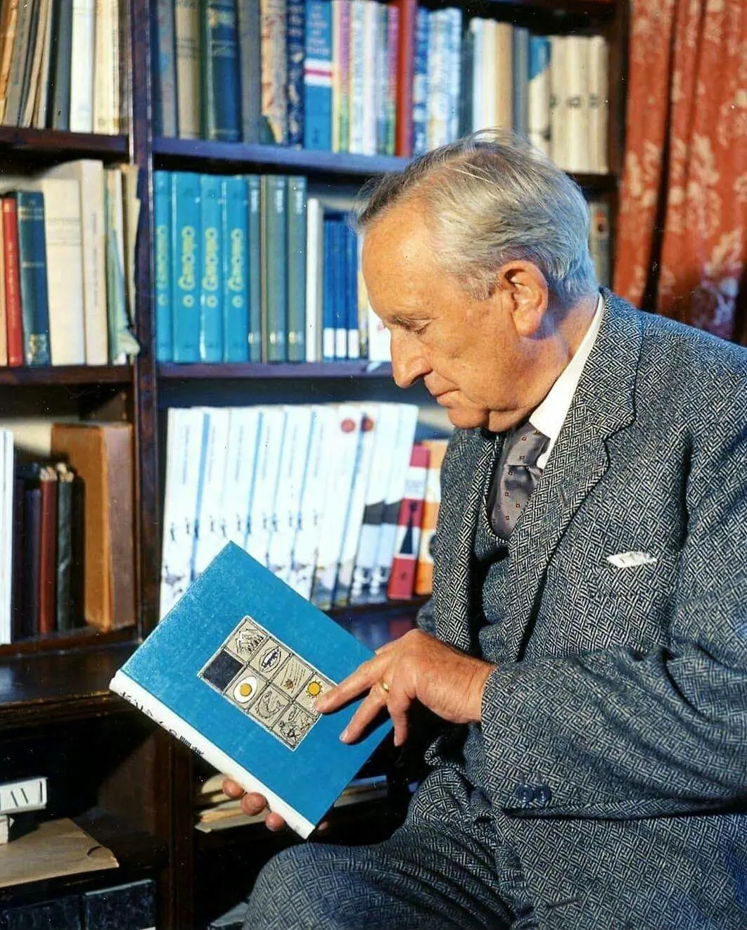 Photo : John Ronald Reuel Tolkien, feuilletant un livre de sa bibliothèque, au 76 Sandfield Road à Oxford, année 1961.
